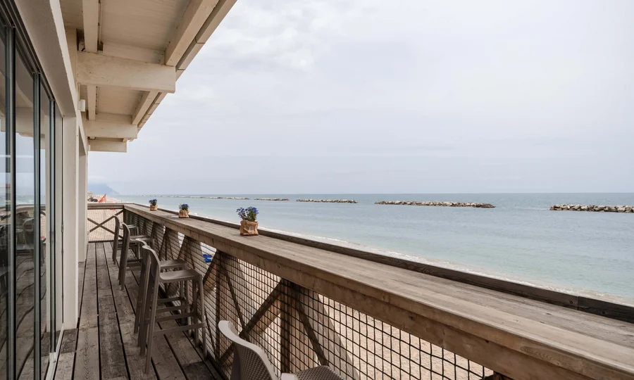 Un villaggio nelle Marche sul mare: il Natural Village Resort Terrazza in legno con sedie fronte mare e piccole piante in vaso