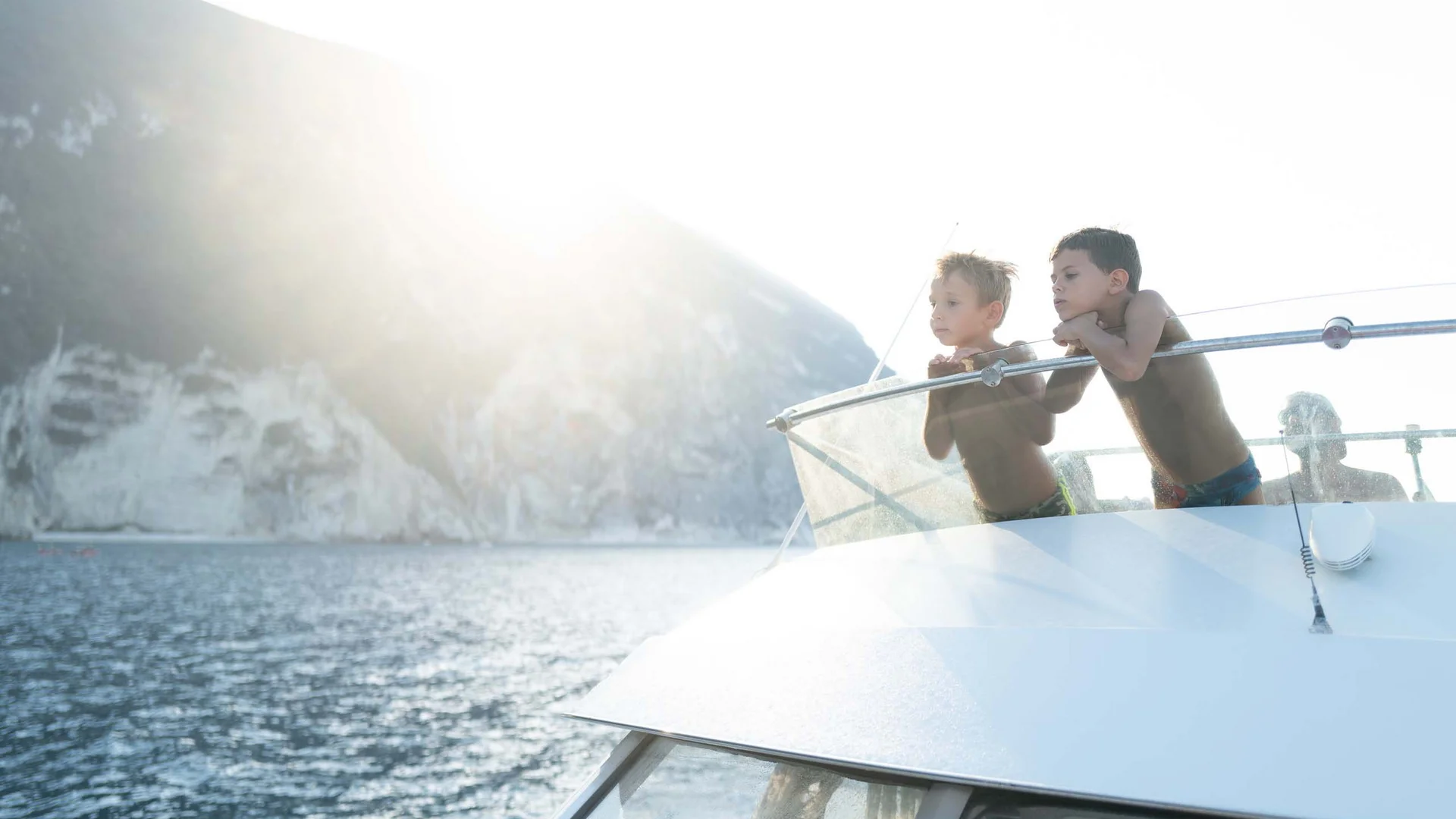 Un villaggio nelle Marche sul mare: il Natural Village Resort Due bambini guardano dal ponte di una barca verso il mare e le scogliere