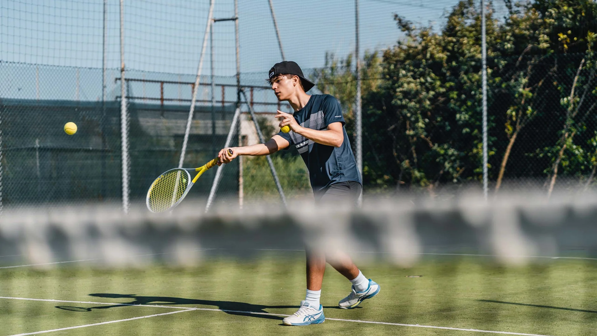 Un villaggio nelle Marche sul mare: il Natural Village Resort Giocatore di tennis che colpisce una palla su un campo all'aperto